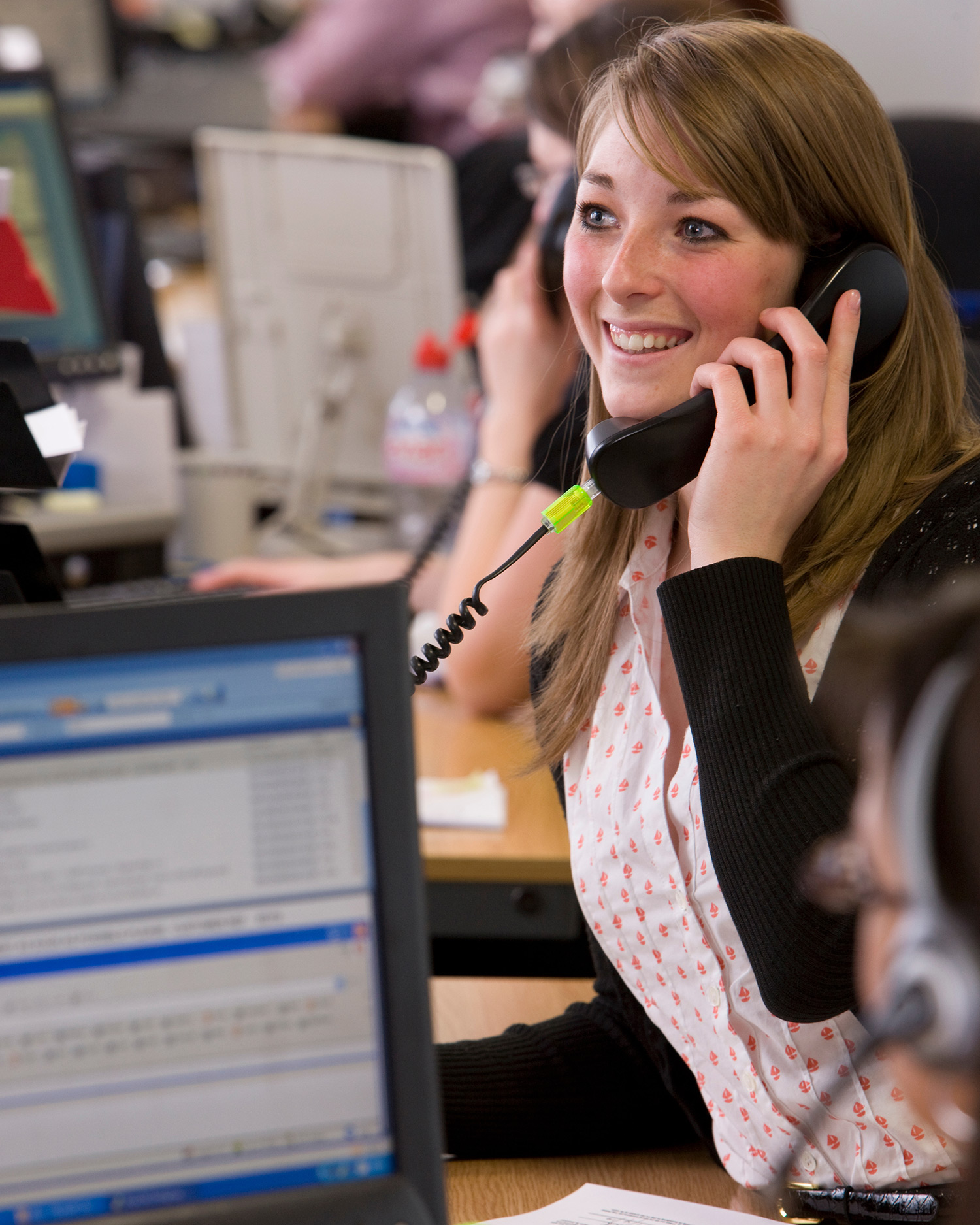 Customer service representative speaking on the phone in a busy office, assisting with freight and logistics enquiries